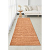 Rust textured rug on a light gray floor in a living room setting with a white sofa and small table.
