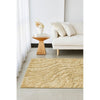 Gold textured rug in a living room setting with a white sofa and wooden side table.