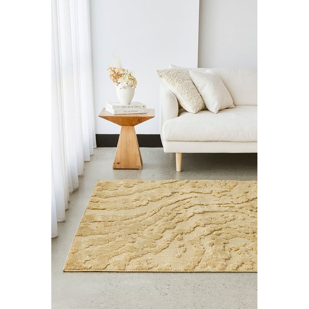 Gold textured rug in a living room setting with a white sofa and wooden side table.