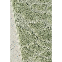 Close-up of a textured green runner rug on a concrete floor