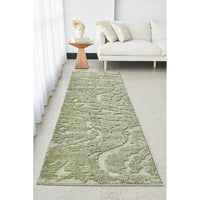 Green runner rug on a light gray floor in a living room setting with a white sofa and wooden side table.