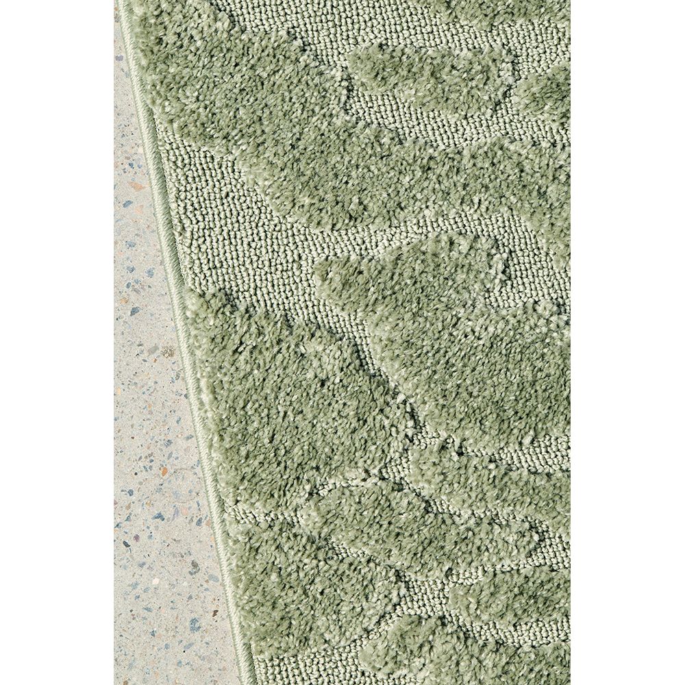 Close-up of a textured green rug on a concrete floor