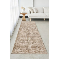 Beige runner rug on a light gray floor in a living room setting with a white sofa and wooden side table.