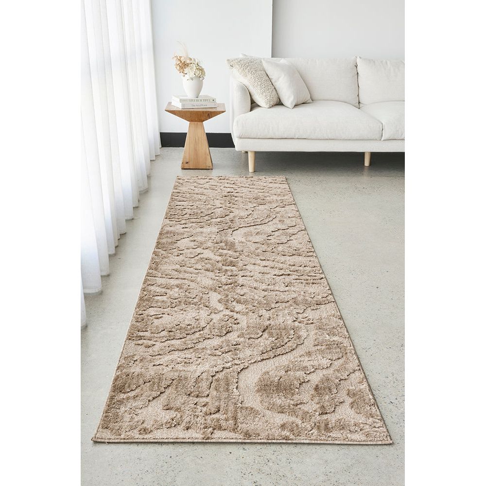 Beige runner rug on a light gray floor in a living room setting with a white sofa and wooden side table.