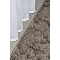 Close-up of a textured brown rug with a white curtain in the background