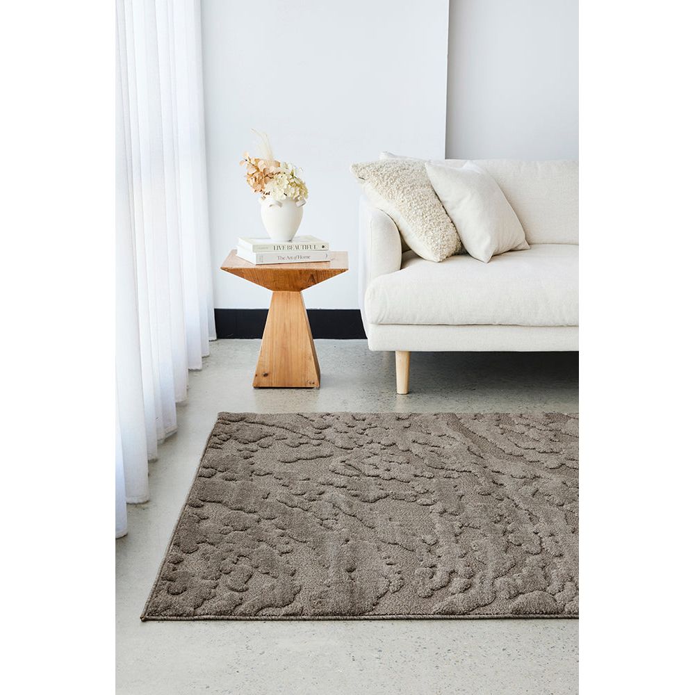 Living room with a textured mocha brown rug, white sofa, and wooden side table.