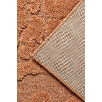 Close-up of a rust coloured textured rug with a corner overlap.
