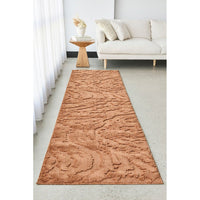 Textured rust coloured runner rug on a light gray floor in a living room setting.