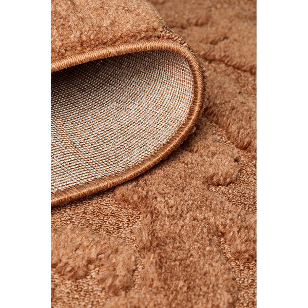 Close-up of rust orange textured polyester rug with subtle modern geometric pattern and 12mm pile depth.