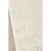 Close-up of a textured white rug on a concrete floor