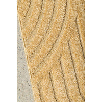 Close-up of a textured gold rug on a concrete floor