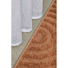 Rust textured rug on a concrete floor with white curtains.