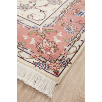 Close-up of a floral patterned rug with tassels on a wooden floor
