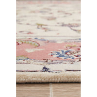 Close-up of a patterned rug with pink and beige colors on a wooden floor.