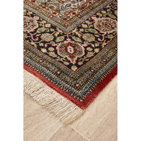 Close-up of a patterned Hand Knotted Silk Rug with fringes on a wooden floor.