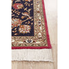 Corner of an ornate Persian rug with floral patterns and fringes on a light wood floor.