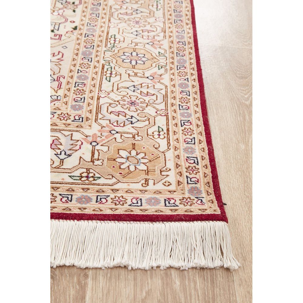 Close-up of a patterned Persian wool rug with fringes on a wooden floor