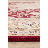 Close-up of a patterned Persian wool rug with red and beige colors on a wooden floor.