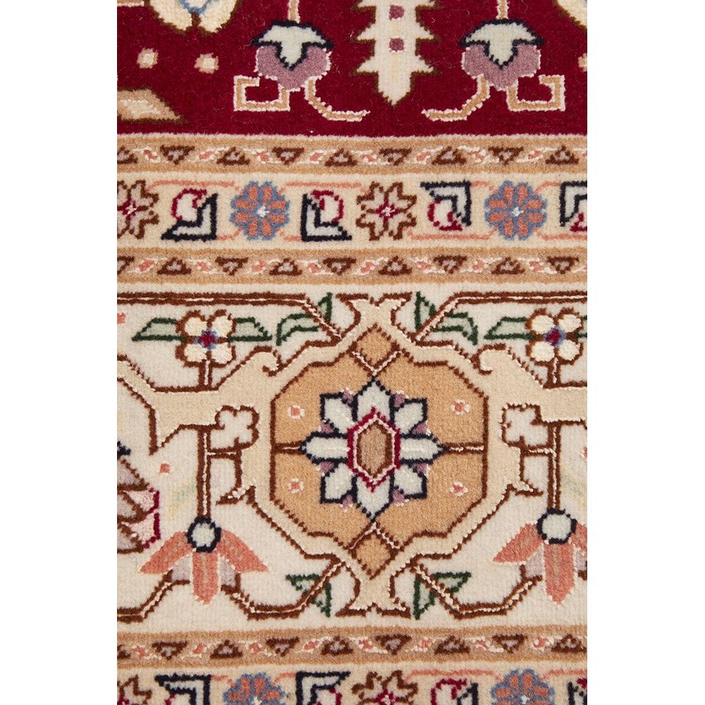 Close-up of a patterned Persian wool rug with geometric and floral designs.