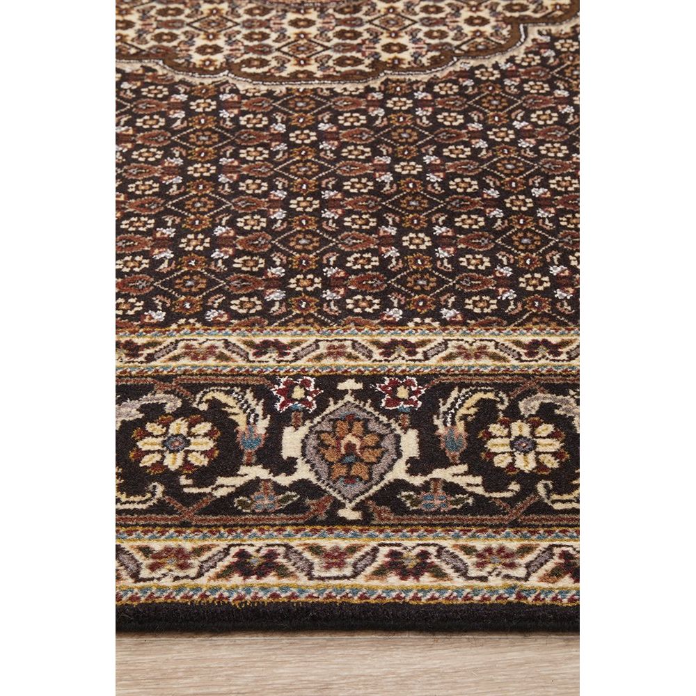 Close-up of a patterned Persian wool rug with intricate designs on a wooden floor.