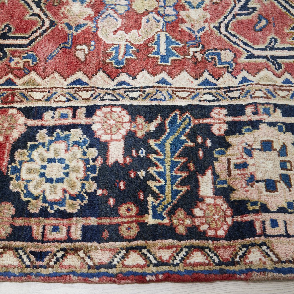 Close-up of an intricately designed Persian wool rug with floral and geometric patterns.