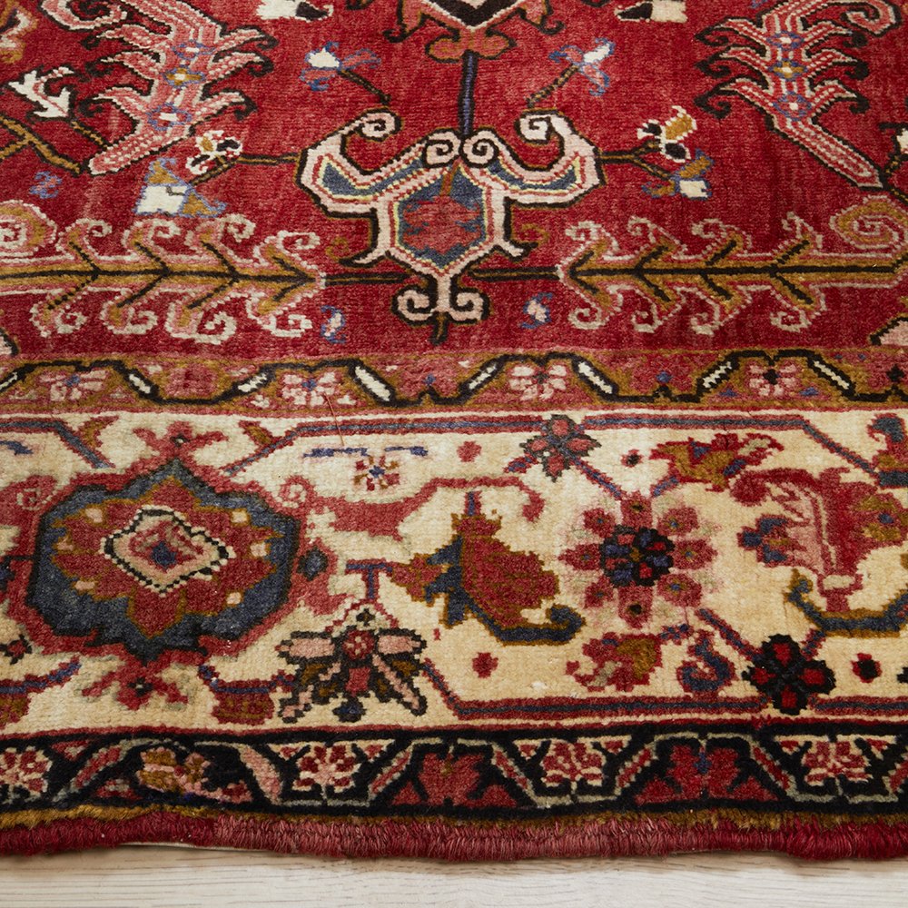 Close-up of a red and beige patterned Persian wool rug with intricate designs.