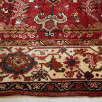 Close-up of a red and beige patterned Persian wool rug with intricate designs.