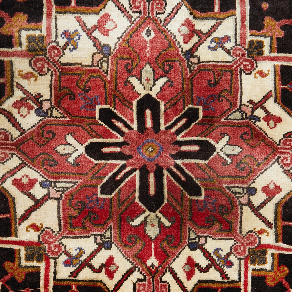 Close-up of a patterned Persian wool rug with red, black, and beige colours.