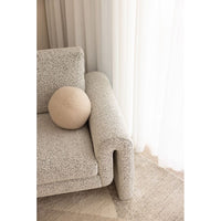 Gray textured sofa with a round beige pillow against a neutral background