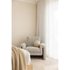 Beige armchair in a room with neutral walls and curtains