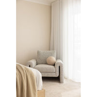Beige armchair in a room with neutral walls and curtains