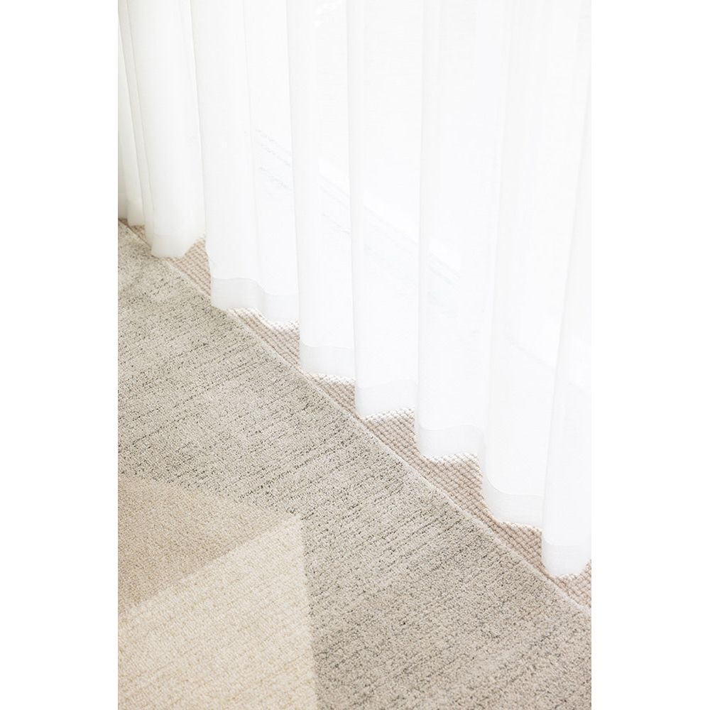 Close-up of a textured beige carpet with a white baseboard
