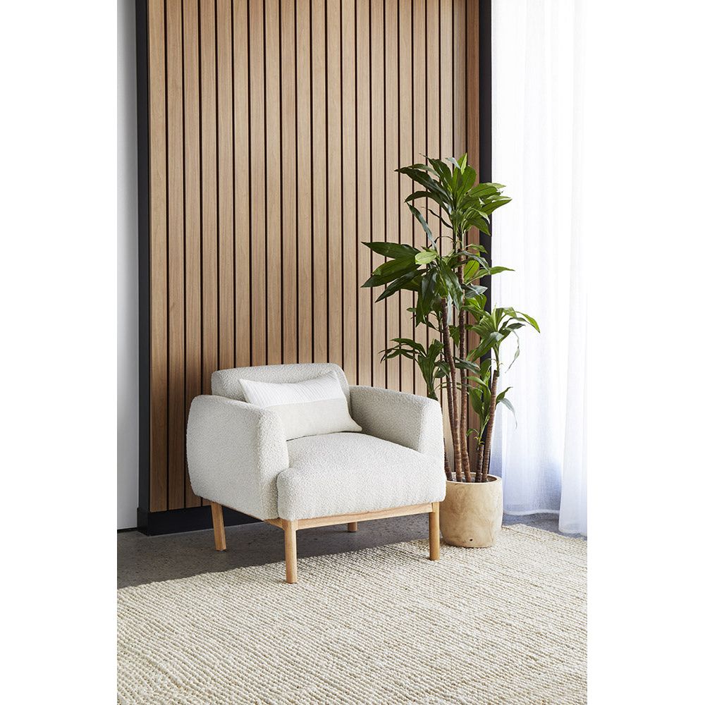 Beige armchair in a room with wooden slat wall and potted plant