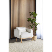 Beige armchair in a room with wooden slat wall and potted plant