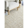Beige textured rug with a chair and plant in the background