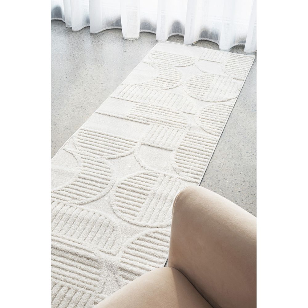 White runner rug with raised geometric patterns in neutral tones on a modern textured surface.