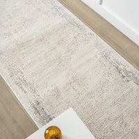Beige and cream textured runner rug with subtle abstract patterns and distressed edges on hardwood floor.