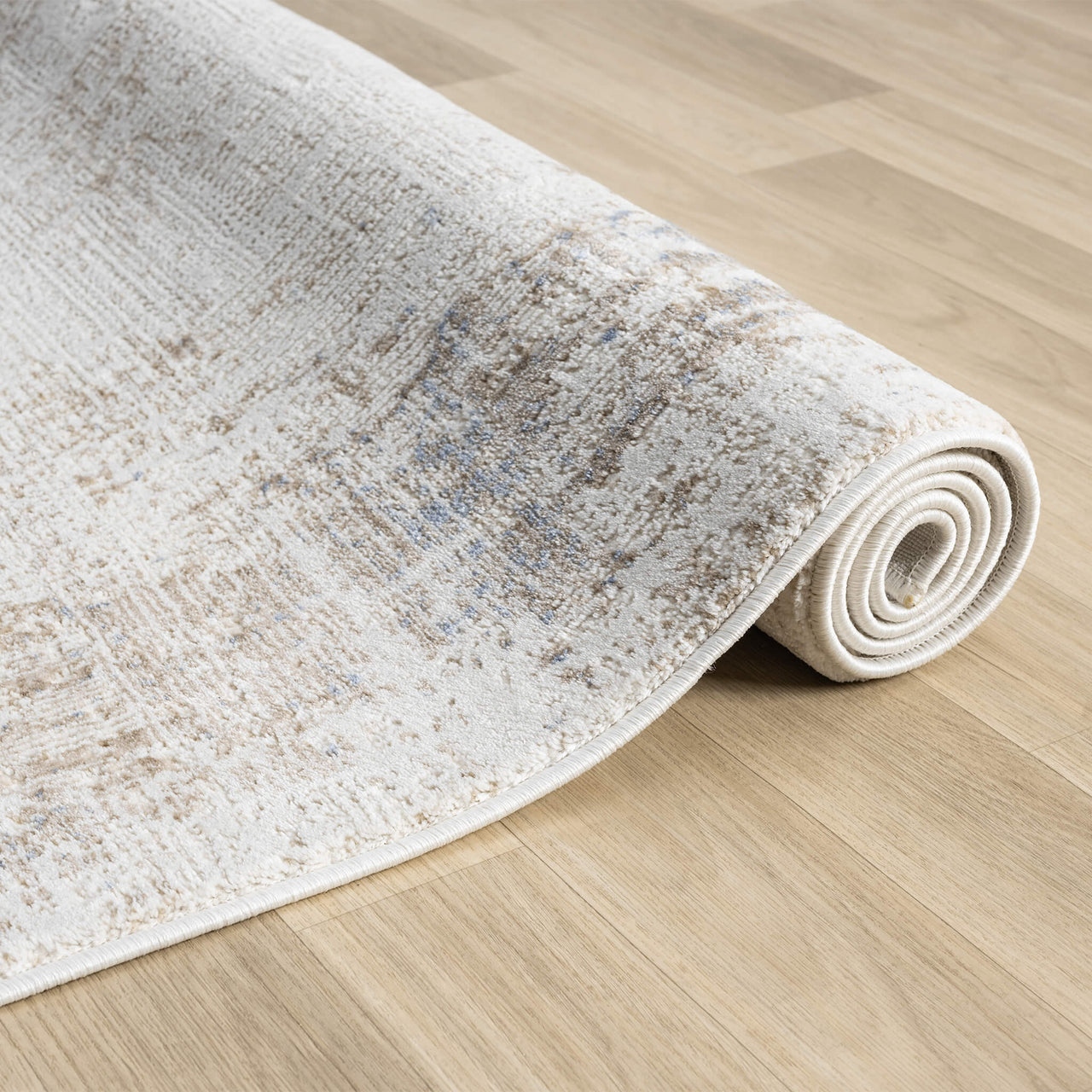 Beige and cream abstract textured modern rug with subtle multi-colored accents rolled on light wood floor.