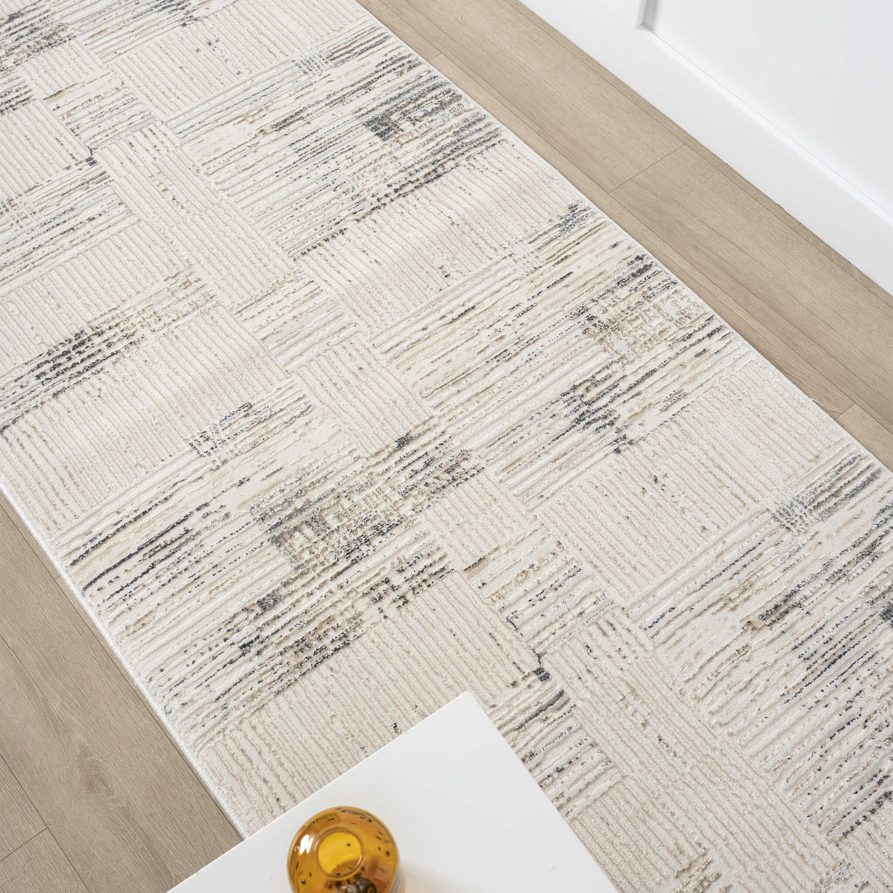 Beige and grey textured modern runner rug with abstract linear pattern on light hardwood floor.