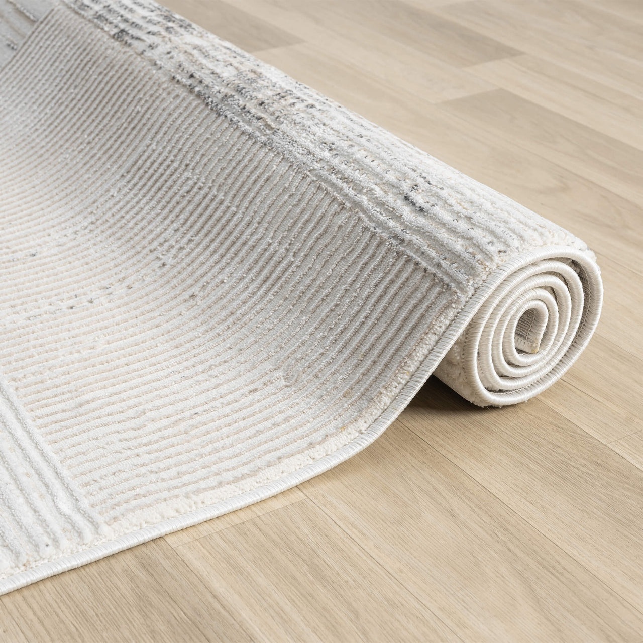Beige and grey textured runner rug with subtle linear patterns, rolled on light wood floor.