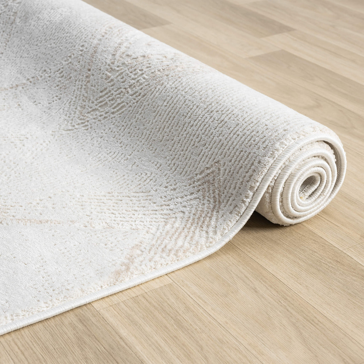 Beige and white modern rug with subtle textured pattern, rolled on light wood floor.