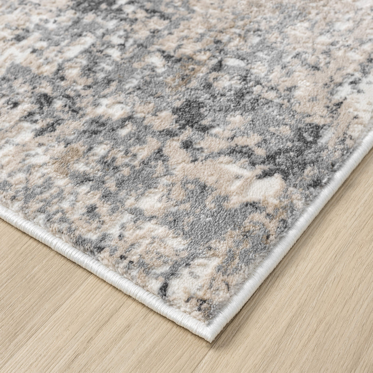 Beige and grey modern rug with abstract pattern and plush texture on wood floor.