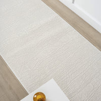 Cream modern runner rug with subtle textured pattern on light wood floor.