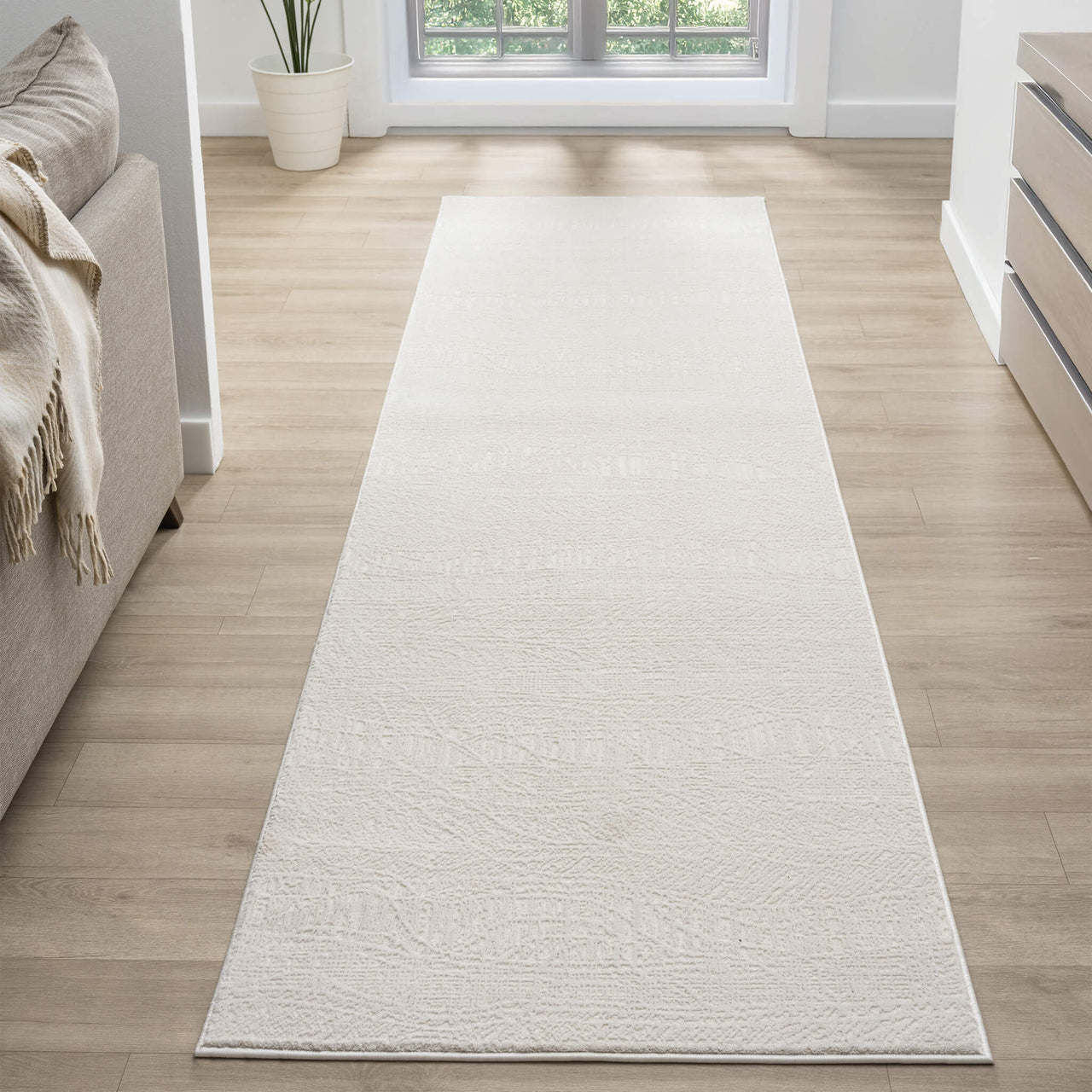 Cream modern runner rug with subtle textured pattern on light wood floor in bright hallway.