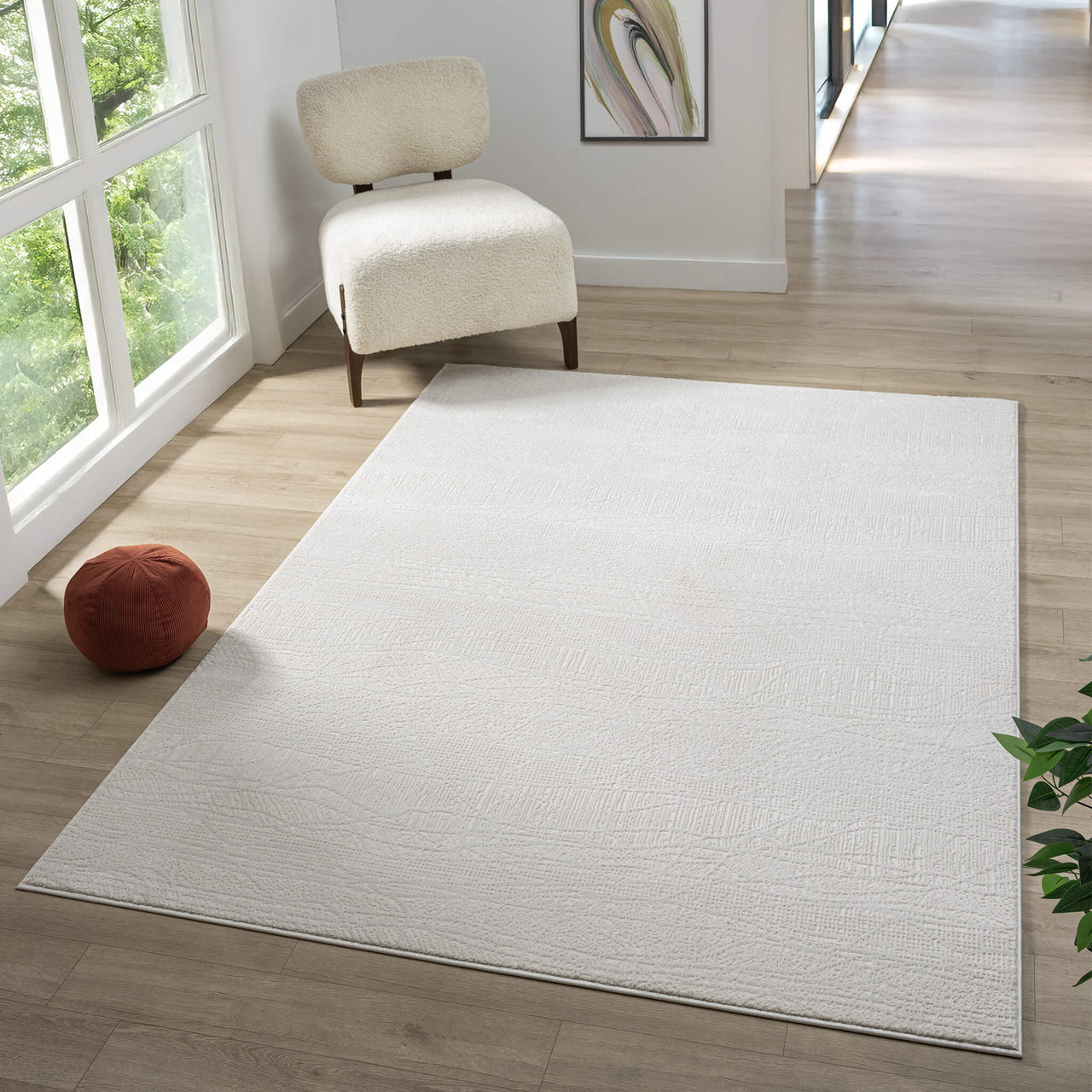 Cream modern rug with subtle textured pattern on light wood floor in bright room.