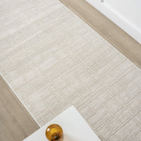 Cream modern runner rug with subtle geometric square patterns on light wood floor.