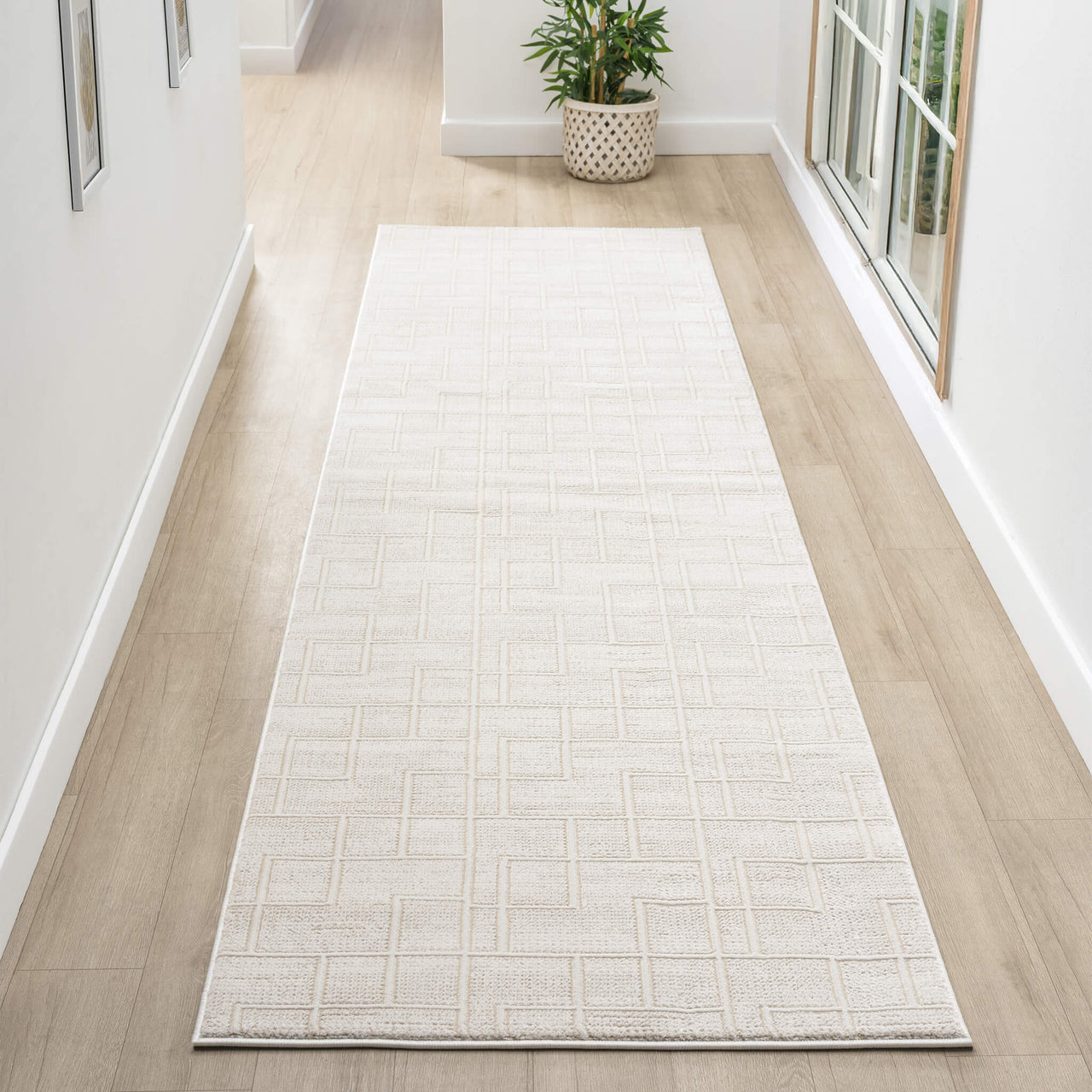 Cream modern runner rug with subtle textured geometric pattern on light hardwood floor in bright hallway.
