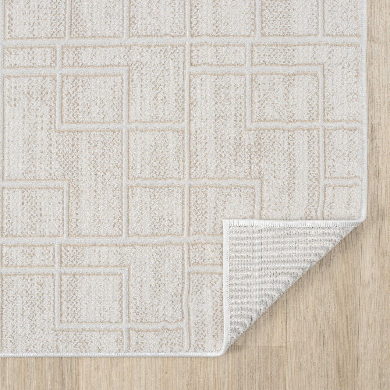Cream modern runner rug with geometric square pattern and textured weave on light wood floor, corner folded to show backing.
