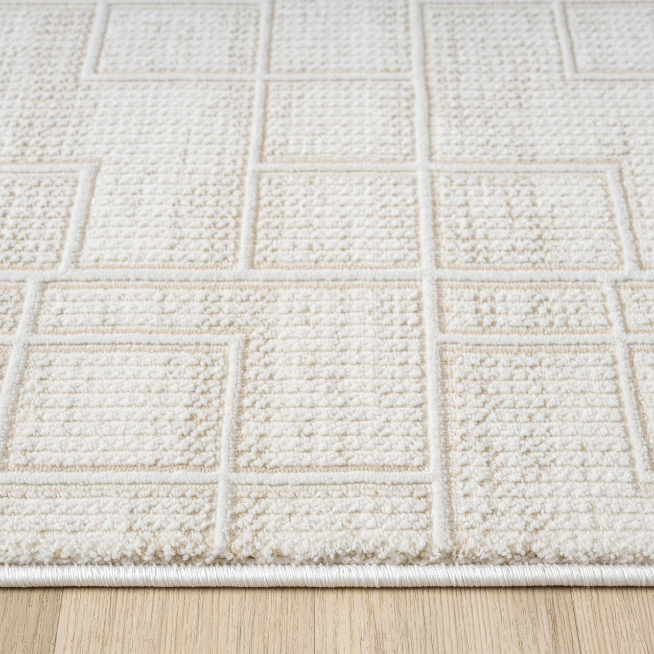 Cream runner rug with textured geometric square pattern on wooden floor.