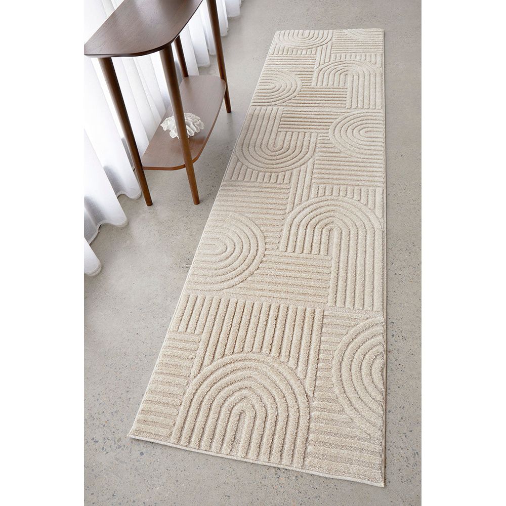 Beige patterned rug on a light gray floor with a wooden side table.